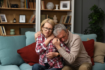 Senior couple husband and wife man and woman, hugs seriously ill woman for support feels her pain...