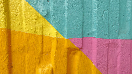 Detail of a wall painted in four colours: blue, yellow, orange and pink. Meant as multi coloured background.