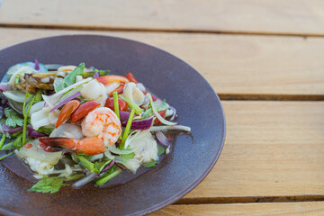 Spicy seafood salad, popular food on a wooden table, appetizing in a cafe next to the sea, Sue Flamingo, Ao Yon Beach, Phuket Thailand