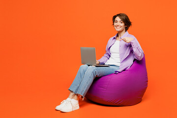 Full body young IT woman she wears purple shirt white t-shirt casual clothes sit in bag chair hold...