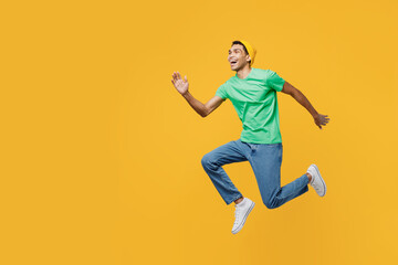 Fototapeta na wymiar Full body side view excited young man of African American ethnicity wear casual clothes green t-shirt hat jump high look aside isolated on plain yellow background studio portrait. Lifestyle concept.