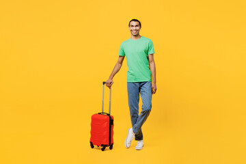 Traveler fun man wearing casual clothes green t-shirt hat holding suitcase isolated on plain yellow...