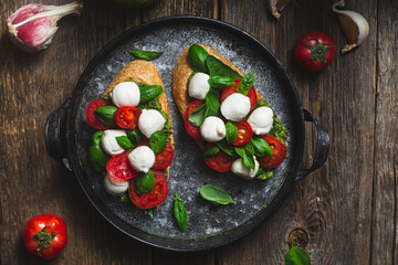 Bruschetta with mozzarella, tomatoes, basil and pesto in a plate. Bruschetta Caprese