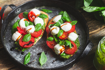 Bruschetta with mozzarella, tomatoes, basil and pesto in a plate. Bruschetta Caprese