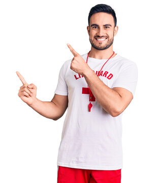 Young Handsome Man Wearing Lifeguard Uniform Smiling And Looking At The Camera Pointing With Two Hands And Fingers To The Side.