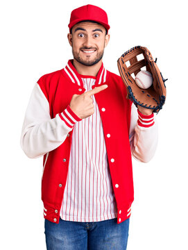 Young handsome man holding baseball gloves smiling happy pointing with hand and finger