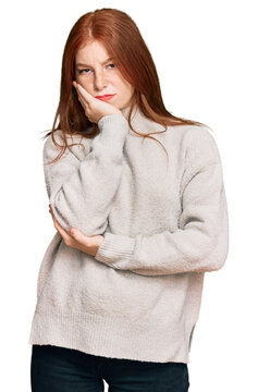 Young read head woman wearing casual winter sweater thinking looking tired and bored with depression problems with crossed arms.