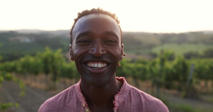 Young african man smiling on camera outdoor with vineyards in background - Travel concept