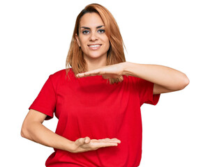 Hispanic young woman wearing casual red t shirt gesturing with hands showing big and large size sign, measure symbol. smiling looking at the camera. measuring concept.