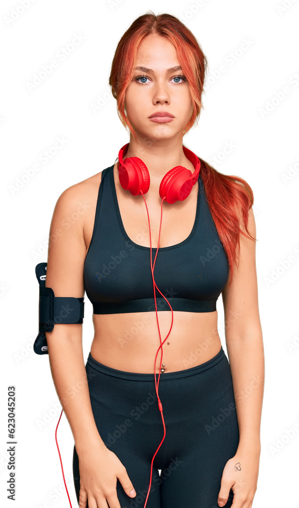 Canvas Prints young redhead woman wearing gym clothes and using headphones with serious expression on face. simple