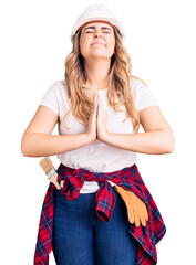 Young caucasian woman wearing security helmet begging and praying with hands together with hope expression on face very emotional and worried. begging.