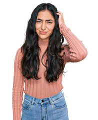 Fototapeta premium Hispanic teenager girl with dental braces wearing casual clothes confuse and wonder about question. uncertain with doubt, thinking with hand on head. pensive concept.