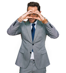 Fototapeta premium Middle age man wearing business clothes doing heart shape with hand and fingers smiling looking through sign