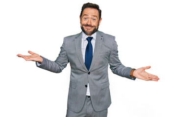 Middle age man wearing business clothes clueless and confused expression with arms and hands raised. doubt concept.