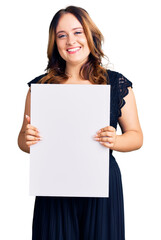 Young beautiful caucasian woman holding cardboard banner with blank space looking positive and happy standing and smiling with a confident smile showing teeth