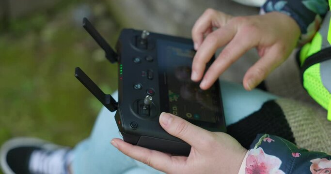 Female hands setting with fingers parameters for photogrammetry on drone remote controller with double antenna