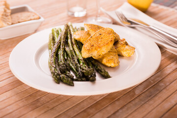 cooked dish. Chicken nuggets with green asparagus on plate