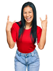 Beautiful hispanic woman wearing casual clothes shouting with crazy expression doing rock symbol with hands up. music star. heavy concept.