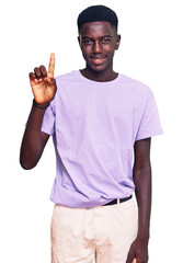 Young african american man wearing casual clothes showing and pointing up with finger number one while smiling confident and happy.