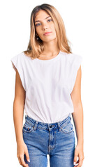Beautiful caucasian woman with blonde hair wearing casual white tshirt relaxed with serious expression on face. simple and natural looking at the camera.