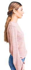 Beautiful caucasian woman with blonde hair wearing casual winter sweater looking to side, relax profile pose with natural face with confident smile.