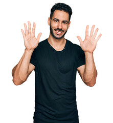 Fototapeta premium Hispanic man with beard wearing casual black t shirt showing and pointing up with fingers number ten while smiling confident and happy.