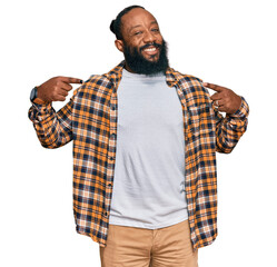 Young african american man wearing casual clothes looking confident with smile on face, pointing...