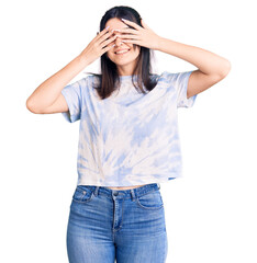 Fototapeta premium Young beautiful girl wearing casual t shirt covering eyes with hands smiling cheerful and funny. blind concept.