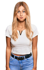 Obraz premium Beautiful blonde young woman wearing casual white tshirt puffing cheeks with funny face. mouth inflated with air, crazy expression.