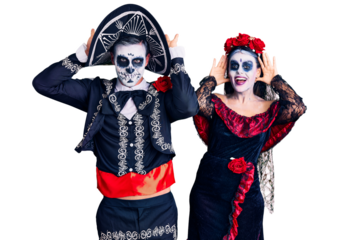 Young couple wearing mexican day of the dead costume over background smiling cheerful playing peek a boo with hands showing face. surprised and exited