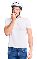Young handsome man wearing bike helmet looking stressed and nervous with hands on mouth biting nails. anxiety problem.