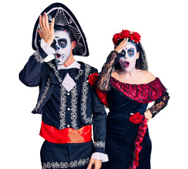Young couple wearing mexican day of the dead costume over background surprised with hand on head for mistake, remember error. forgot, bad memory concept.