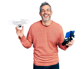 Middle age hispanic man with grey hair using drone with remote control smiling and laughing hard out loud because funny crazy joke.