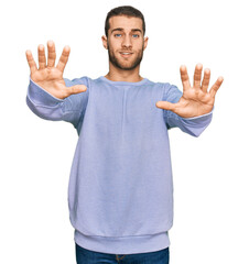 Naklejka premium Young caucasian man wearing casual clothes afraid and terrified with fear expression stop gesture with hands, shouting in shock. panic concept.