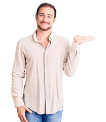Young handsome caucasian man wearing casual clothes smiling cheerful presenting and pointing with palm of hand looking at the camera.