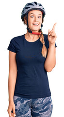 Beautiful caucasian woman wearing bike helmet showing and pointing up with finger number one while smiling confident and happy.