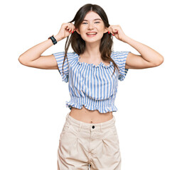 Young beautiful caucasian girl wearing casual clothes smiling pulling ears with fingers, funny...