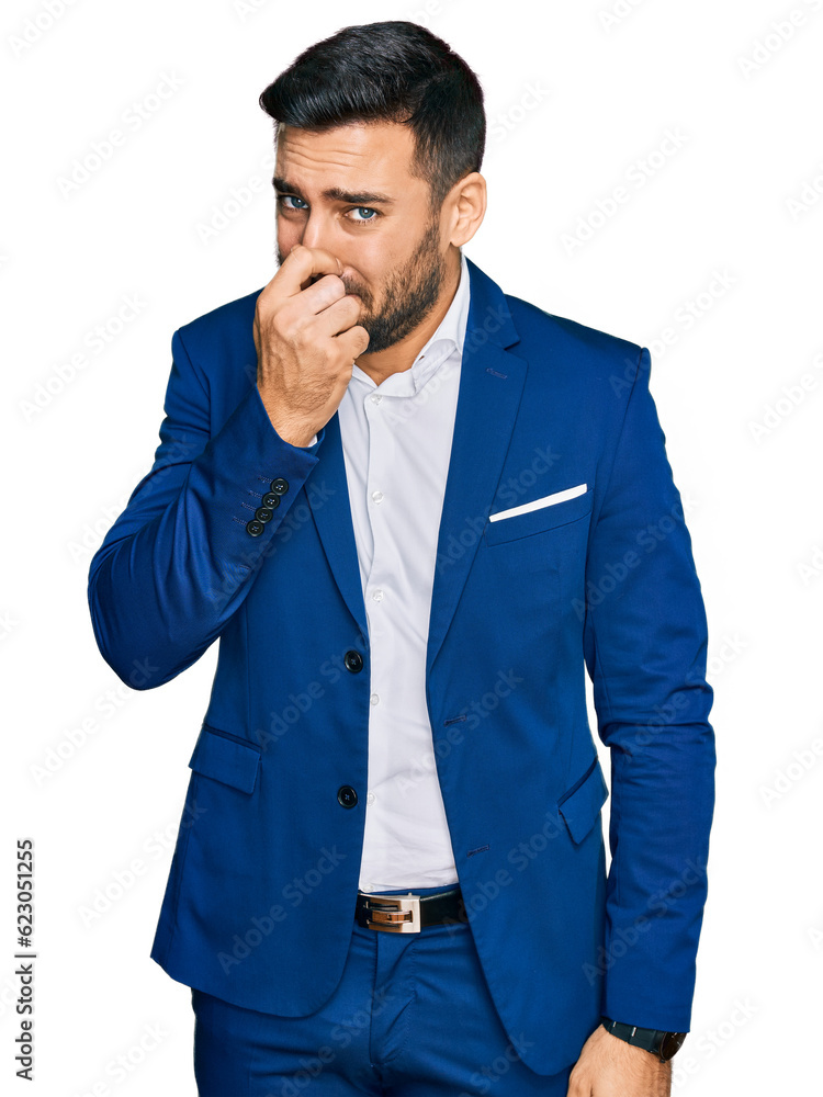 Sticker young hispanic man wearing business jacket smelling something stinky and disgusting, intolerable sme