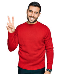 Young hispanic man wearing casual clothes smiling looking to the camera showing fingers doing victory sign. number two.