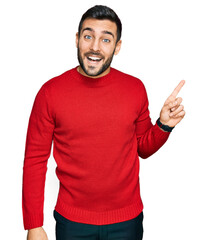 Fototapeta premium Young hispanic man wearing casual clothes with a big smile on face, pointing with hand finger to the side looking at the camera.