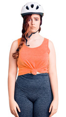 Young beautiful woman wearing bike helmet with serious expression on face. simple and natural looking at the camera.