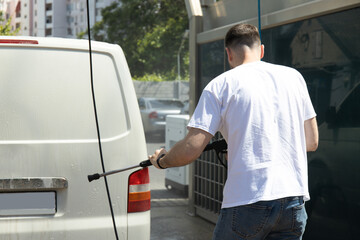 A man washes a car at a self-service car wash