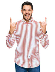 Young hispanic man wearing business shirt shouting with crazy expression doing rock symbol with hands up. music star. heavy concept.