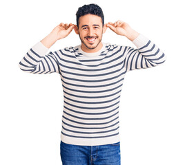 Young hispanic man wearing casual clothes smiling pulling ears with fingers, funny gesture. audition problem