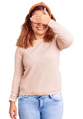 Fototapeta premium Young latin woman wearing casual clothes and diadem smiling and laughing with hand on face covering eyes for surprise. blind concept.
