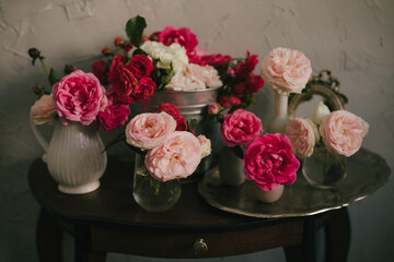 Still life with many different garden roses on a vintage table on grey background.