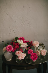 Still life with many different garden roses on a vintage table on grey background.