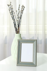 A photo frame with a vase on the table, near the window