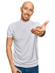 Bald man with beard wearing casual white t shirt smiling friendly offering handshake as greeting and welcoming. successful business.