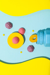 Jelly candies, blue jar on blue-yellow background, top view
